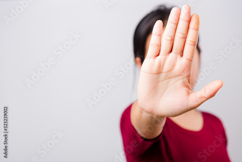 Asian beautiful woman itching her outstretched hand showing stop gesture front face, focus