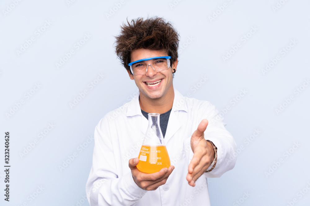 Young scientific man over isolated blue background handshaking after good deal Young scientific man over isolated blue background handshaking after good deal