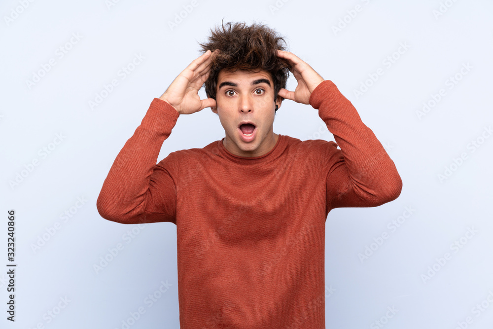 Fototapeta premium Młody człowiek kaukaski na białym tle niebieski z wyrazem zaskoczenia