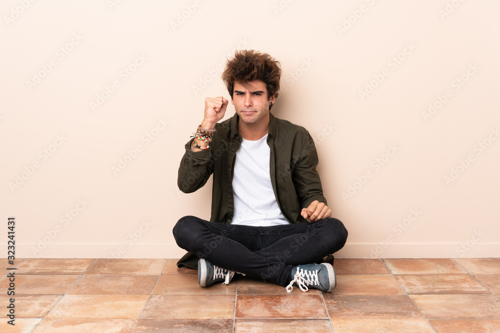 Young caucasian man sitting on the floor with angry gesture Young caucasian man sitting on the floor with angry gesture