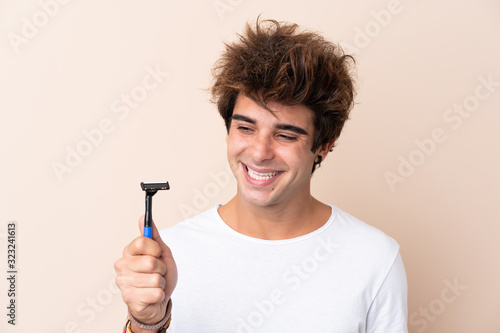 Young handsome man shaving his beard with happy expression