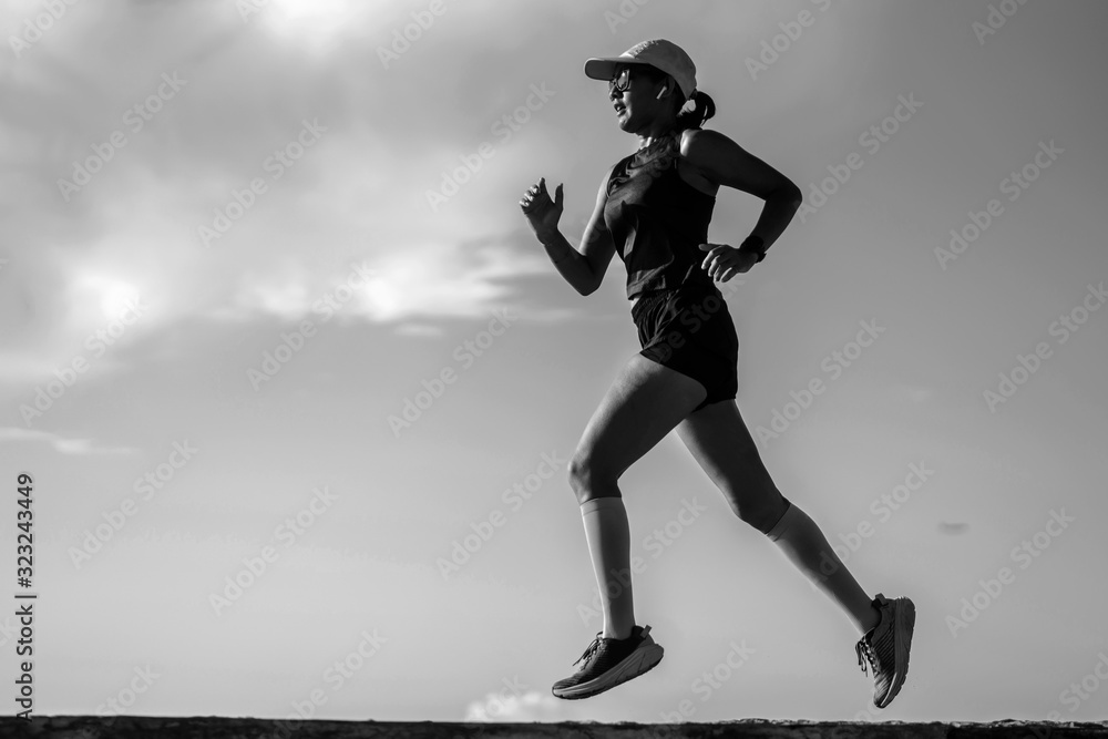 dynamic silhouette of young attractive and athletic woman in compression running socks jogging happy on city park doing intervals workout in athlete training concept