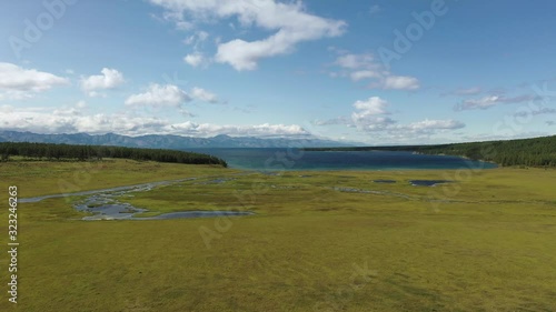 View of the blue lake Hubsugul in Mongolia against the backdrop of mountains, forests, green grass and a beautiful sky with clouds. Feeling of freshness and crystal clear air. photo