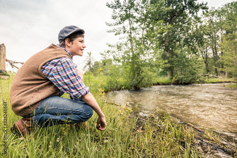 Young boy in retro outfit hanging out in the countryside next to river. Red Lodge, Montana, USA Young boy in retro outfit hanging out in the countryside next to river. Red Lodge, Montana, USA