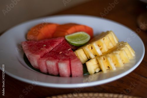 Delicious Organic watermelon, papaya, pineapple pieces in a decorative serving with mint leaves under sunlight during the touristic relaxation in the morning breakfast