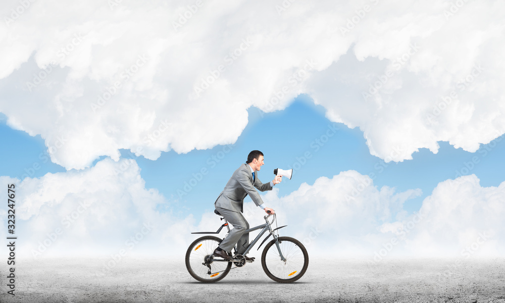 Fototapeta premium Businessman with megaphone on bike