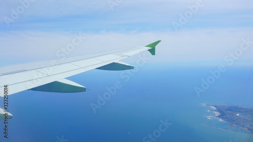 View from the airplane porthole. Landscape: sky, sea, island, airplane wing