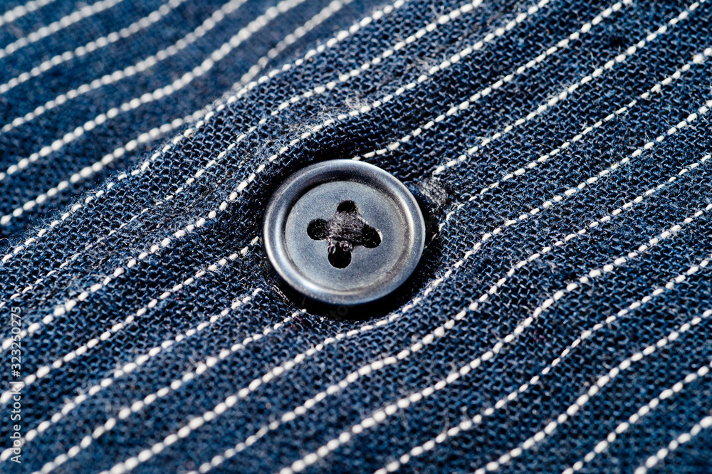 The texture of a denim shirt in dark blue with a small strip on the buttons. Background for fabric and clothes. Fashion, style and practicality. The texture of a denim shirt in dark blue with a small strip on the buttons. Background for fabric and clothes. Fashion, style and practicality.