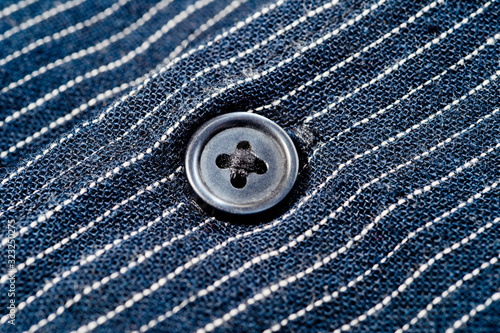 The texture of a denim shirt in dark blue with a small strip on the buttons. Background for fabric and clothes. Fashion, style and practicality.