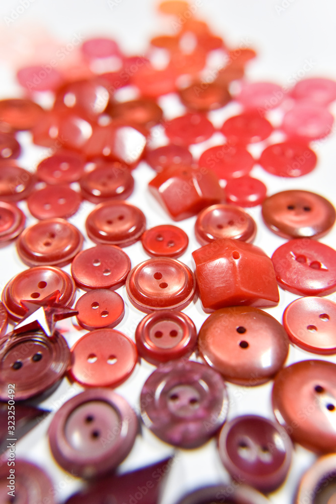 red buttons of different shape and size on the white background. Selective focus.