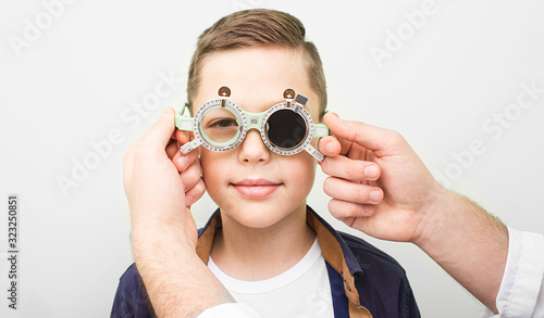Optometrist putting on the boy special glasses to restore visual acuity. Amblyopia treatment in an ophthalmologic clinic photo
