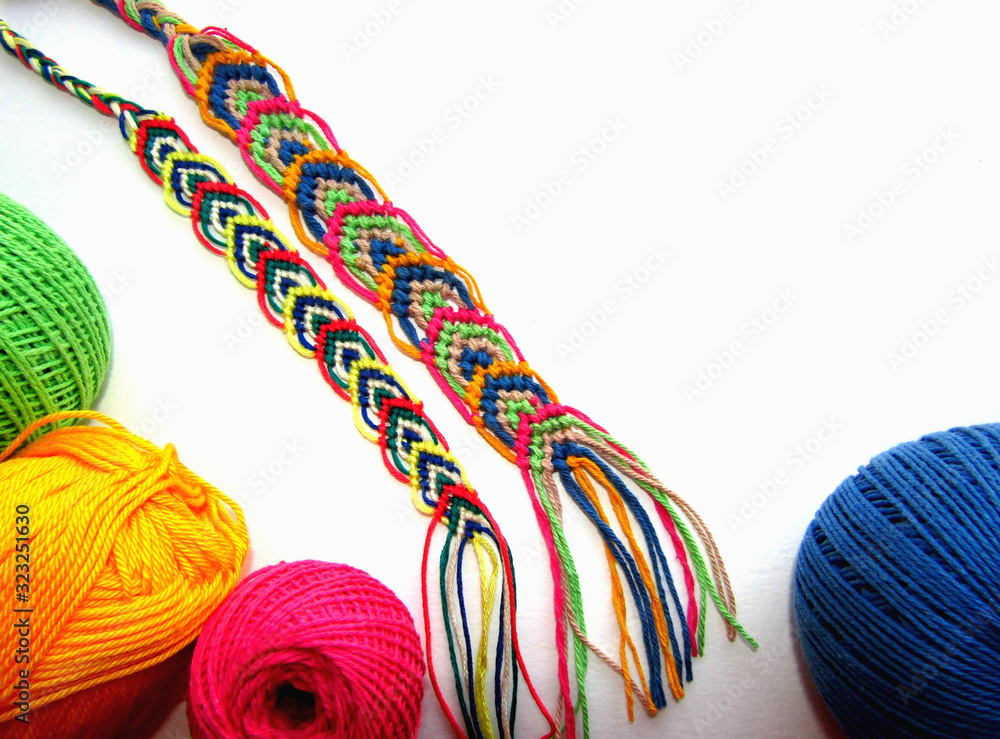 Braided friendship bracelets made of thread with a ball on a white background Braided friendship bracelets made of thread with a ball on a white background