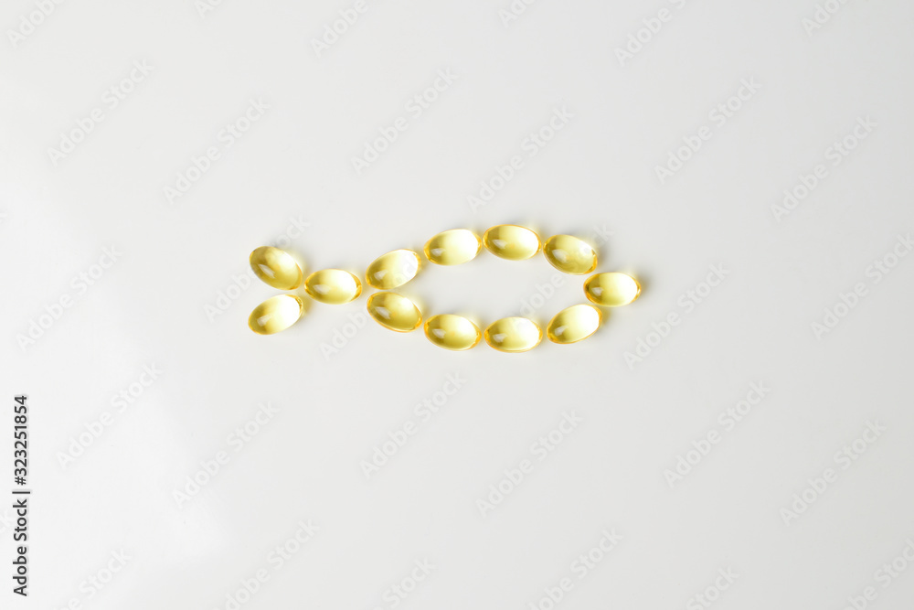 Fish oil softgels on a white background in a shape of a fish. Meal replacement. Nutrition prescription. Omega-3 polyunsaturated fatty acids. Close-up. Fish oil softgels on a white background in a shape of a fish. Meal replacement. Nutrition prescription. Omega-3 polyunsaturated fatty acids. Close-up.