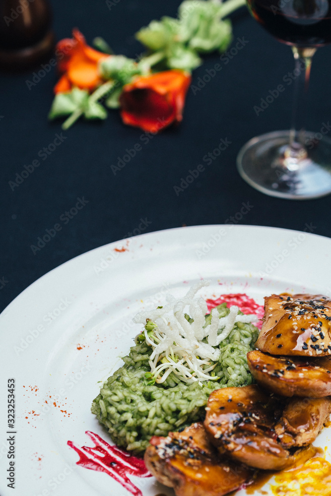chicken with risotto on a white plate with wine a roses chicken with risotto on a white plate with wine a roses