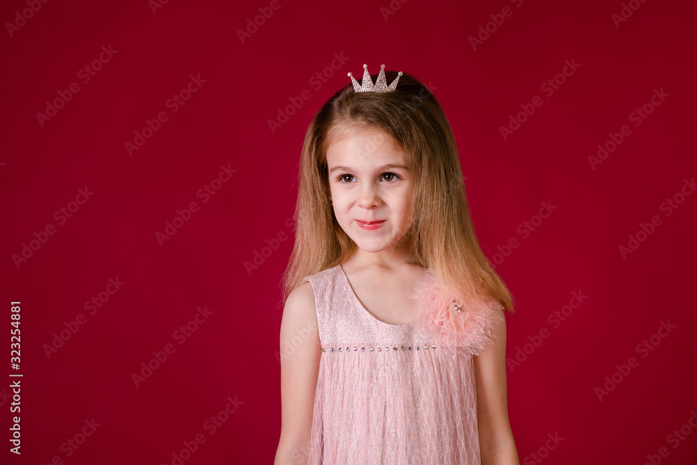 Beautiful little girl princess dancing in luxury pink and silver dress isolated on red background. Funny face, different emotions Beautiful little girl princess dancing in luxury pink and silver dress isolated on red background. Funny face, different emotions