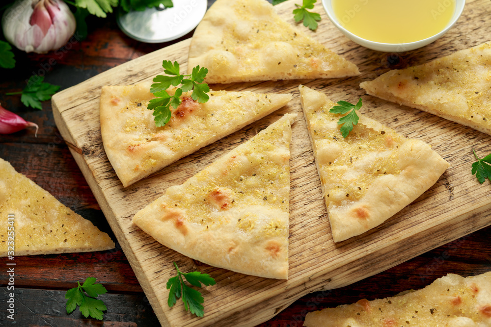 Fresh slices of Garlic pizza on wooden board with herbs. Fresh slices of Garlic pizza on wooden board with herbs.