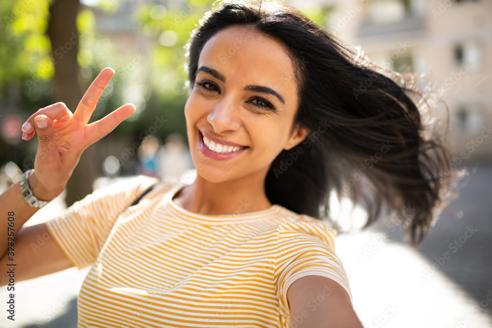 selfie portrait smiling young hispanic woman with peace hand sign