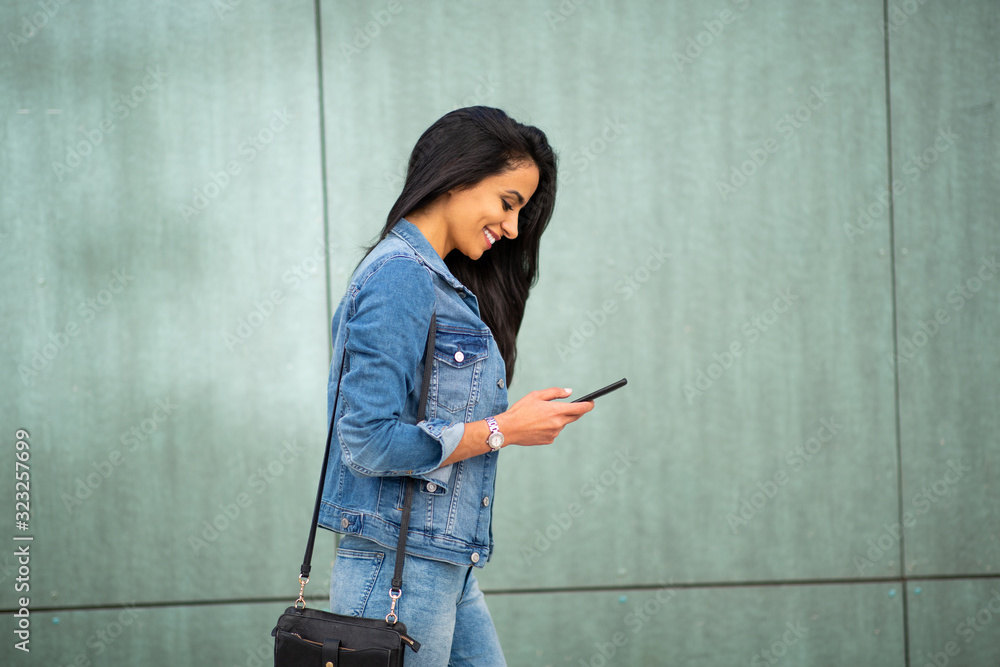 smiling young woman walking with mobile phone and purse smiling young woman walking with mobile phone and purse