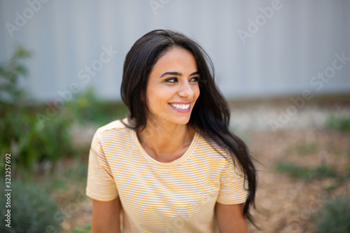 Close up smiling young hispanic woman sitting outside