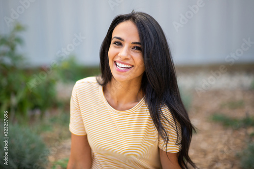 Close up smiling young hispanic woman sitting outdoors
