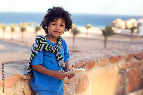 Kid boy playing with tablet outdoor. Children and gadget addiction concept