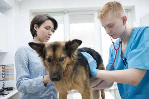 medicine, pet, animals, health care and people concept - happy woman with  dog and veterinarian doctor at vet clinic photo