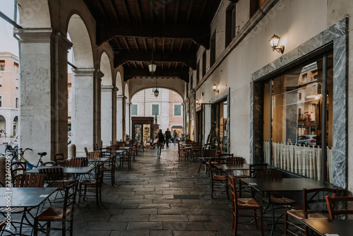 Cozy narrow street with arches and tables of cafe in Ferrara, Emilia-Romagna, Italy. Ferrara is capital of the Province of Ferrara