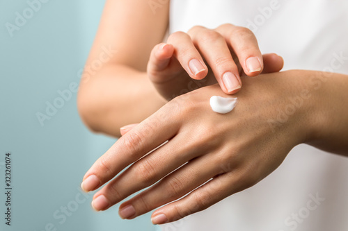 healthy hands and nails. seasonal skin protection. woman applying moisturizer on her hands photo