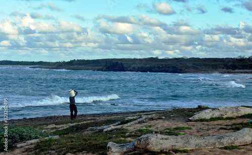 a fisherman walks along a wild beach on the Atlantic ocean coast. Dominican Republic