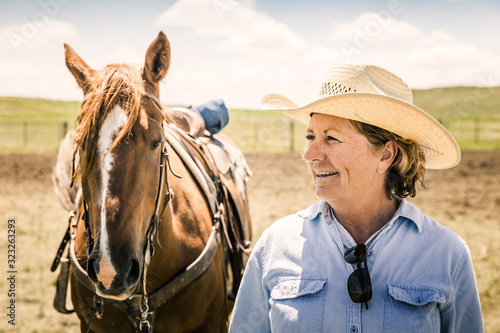 Older cowgirl smiling while holding her horse. Cody, Wyoming, USA photo