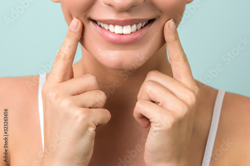 lip protection. close up of a young woman beautiful smile, healthy lips and white teeth on aqua-mint background