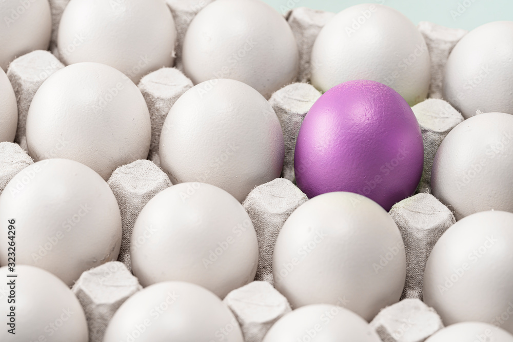 Easter purple red egg among many other identical white ones. the team leader or a loner., symbol of individuality. concept Easter purple red egg among many other identical white ones. the team leader or a loner., symbol of individuality. concept