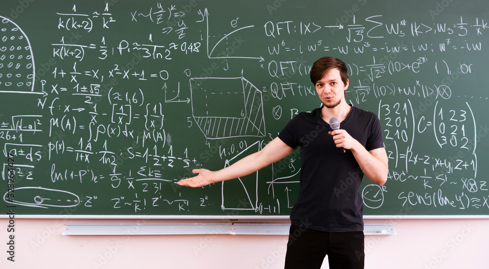 teacher of young professor explains the law of physics for students on the lesson, standing near the blackboard