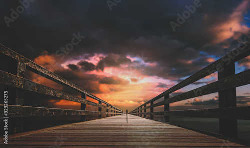 men stand on a wooden Long bridge with afternoon sunset dark clouds background.