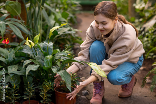 Woman smiling home gardening plants pot in greenhouse