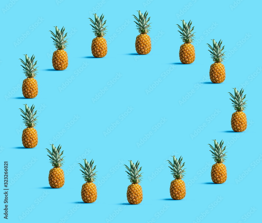 Fototapeta premium Round frame of pineapples on a solid color background