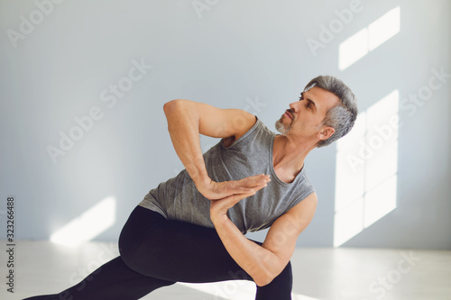 Yoga man. A man is practicing yoga balance in a gray room.