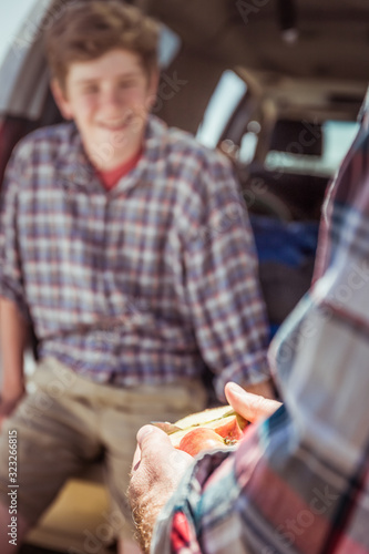 Close-up of father and son out in nature, camping in truck, aeting apple. Bridger, Montana, USA photo