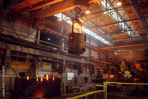 Crane with bucket of liquid metal on steel factory
