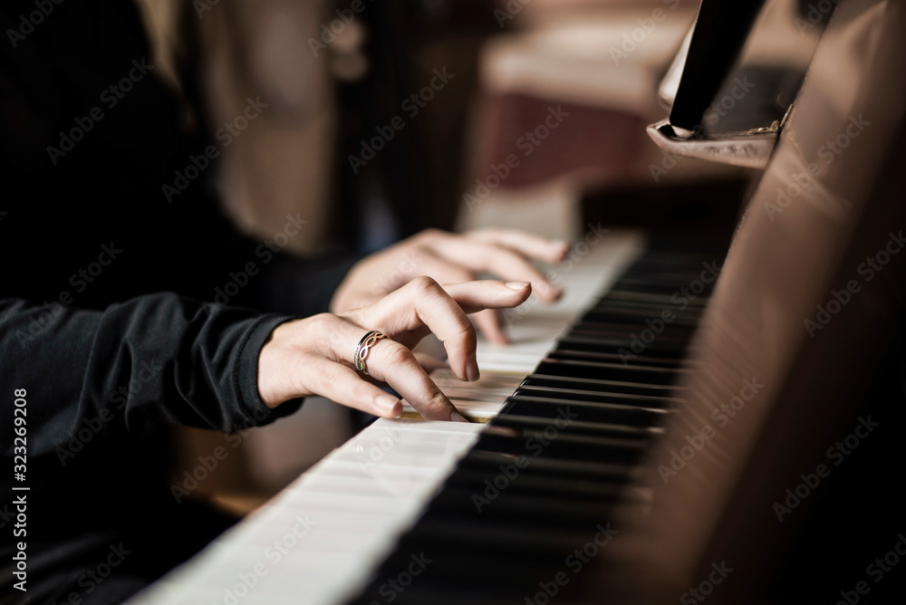 Obraz premium Young girl playing at home on the piano, selective focus on the girl's fingers. When playing the piano, it is easier for a girl to overcome her teenage problems