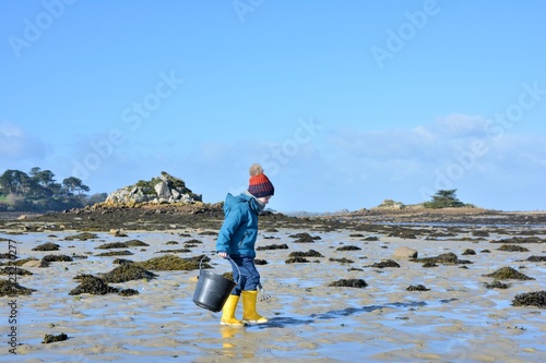 A young boy who is fishing at low tide in Brittany. France Fototapete