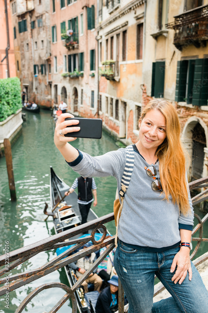 Young female traveler taking a selfie by the canal in Venice, Italy