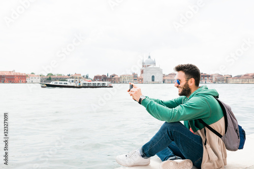 Young traveler sitting on the waterfront enjoying the view of canal in Venice, Italy
