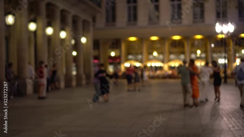 Parisians and tourists dance elegantly in one of the squares of Paris. Bright shop Windows, beautiful building facade decorated with columns, in the background. Outdoor dancing, summer evening, Paris.