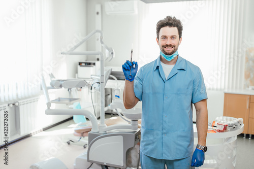 Healthcare, profession, stomatology and medicine concept, male dentist over medical office background, holding syringe.