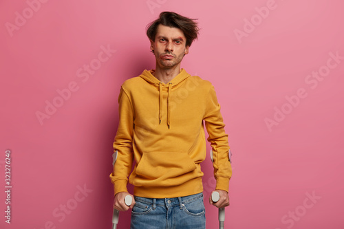 Young male driver distracted by phone during driving, walked on slippery road, poses on crutches. Man pedestrian crashed by car during crossing road, has rehabilitation period in private clinic © wayhome.studio 