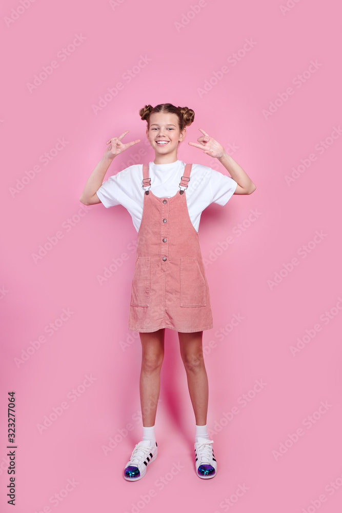 beautiful girl in white t-shirt, pink denim standing with rock horns and looking at camera beautiful girl in white t-shirt, pink denim standing with rock horns and looking at camera