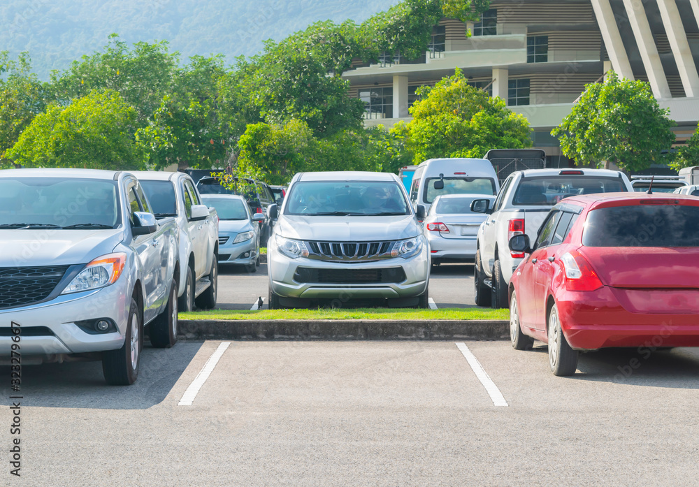 Car parked in asphalt parking lot and one empty space parking in nature with trees and mountain background Car parked in asphalt parking lot and one empty space parking in nature with trees and mountain background