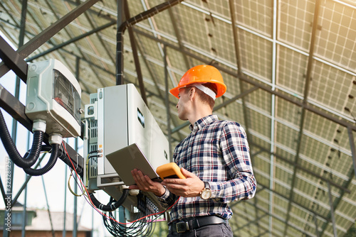 Fotografie Male engineer with laptop sets up equipment at solar power station