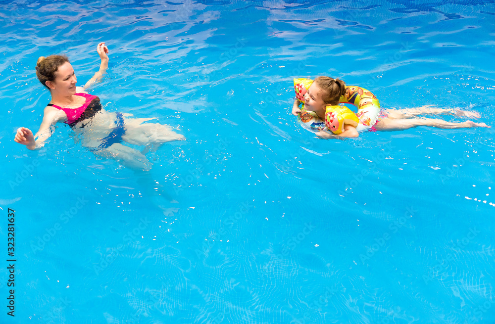 Tween Floating Inpool Kid and mother in water at sea beach. Little girl floating in pool with ...